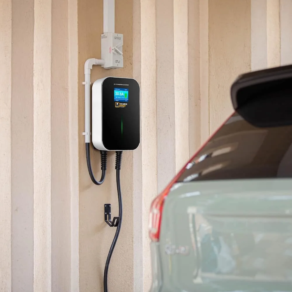 An RSX-1K home EV charger installed on a driveway wall beside a parked car